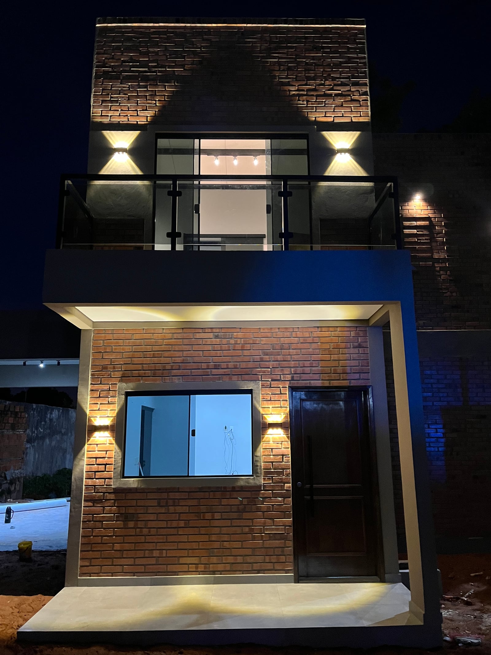 Fachada de la vivienda Mile totalmente iluminada de noche, San Lorenzo - OGA Constructora