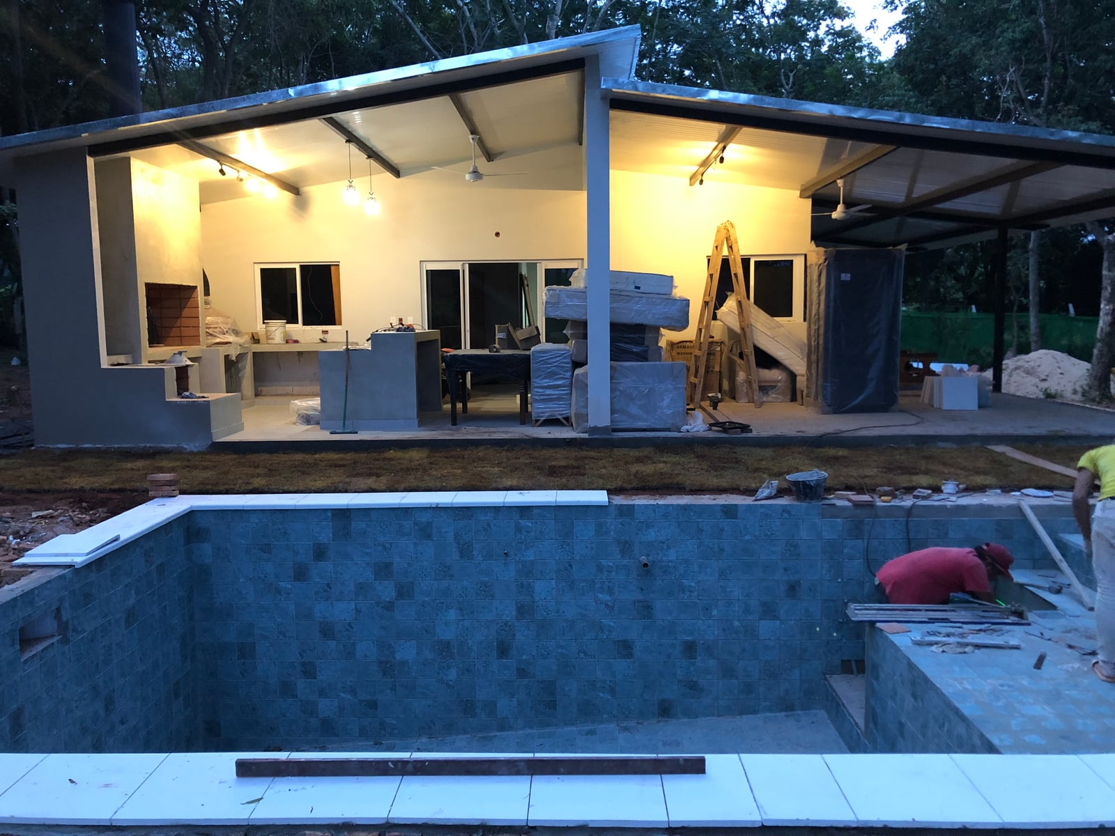 Piscina y quincho iluminados al atardecer en vivienda terminada, Yaguarón - OGA Constructora